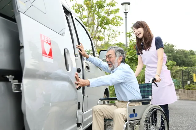 スタッフにサポートされながら介護タクシーに乗り込む車椅子の男性